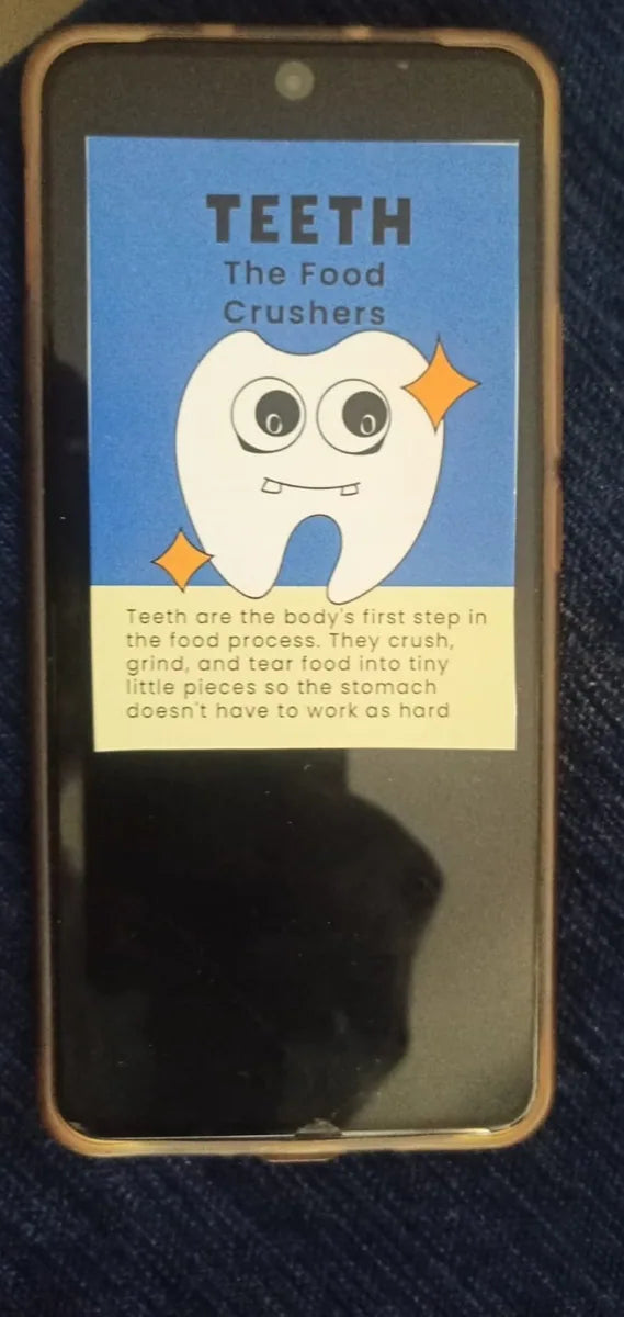 An Oh My Organs Teeth card resting on a switched-off phone, showing the card is about the size of a handset