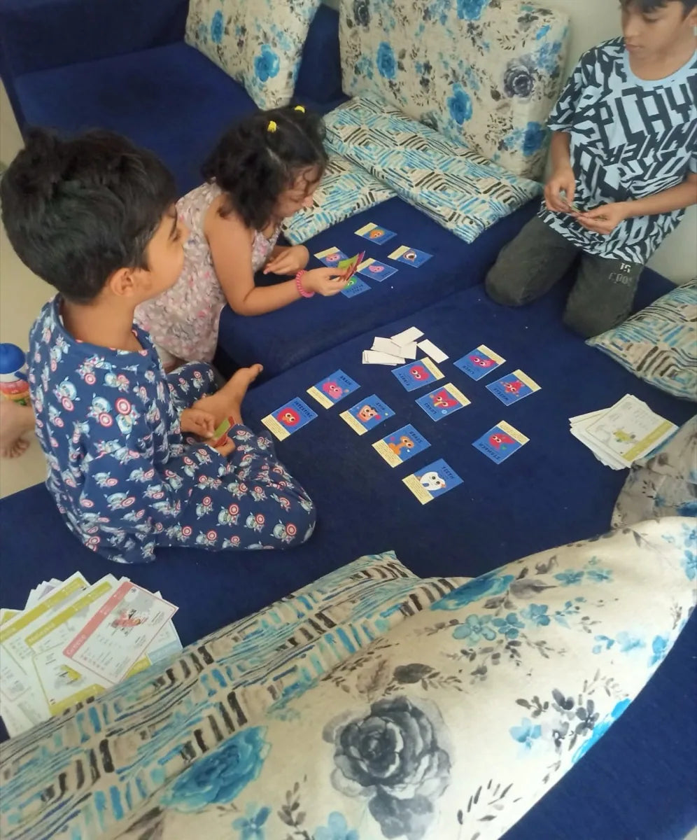 Three children sitting on a sofa with Oh My Organs cards laid out on the seat between them